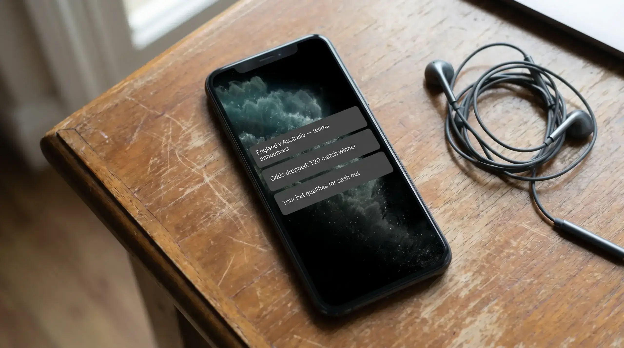 Phone lock screen showing cricket-specific push notifications for team news and odds changes