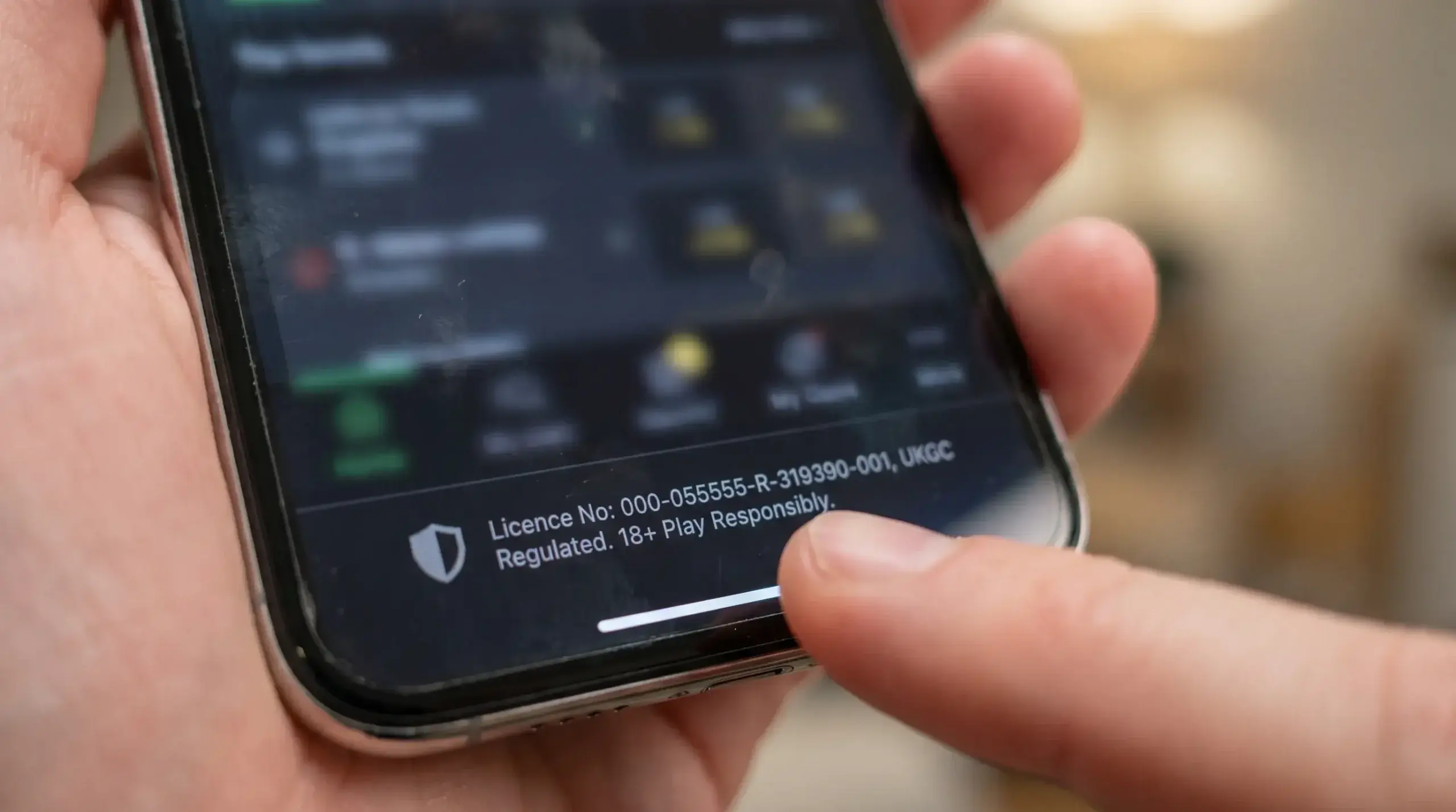 Close-up of a betting app footer displaying a UKGC licence number on a smartphone
